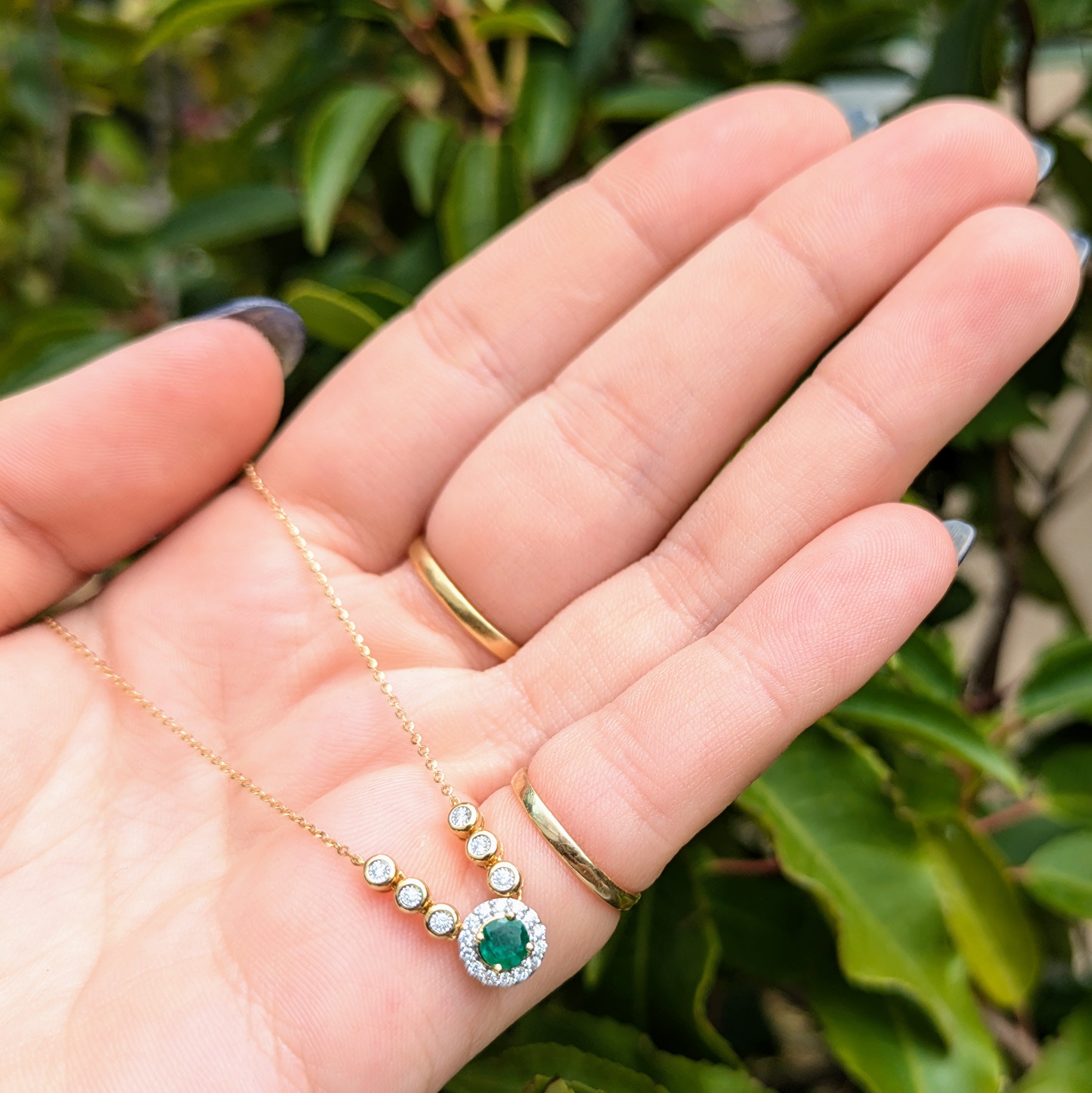 emerald in diamond halo pendant on 18k yellow gold