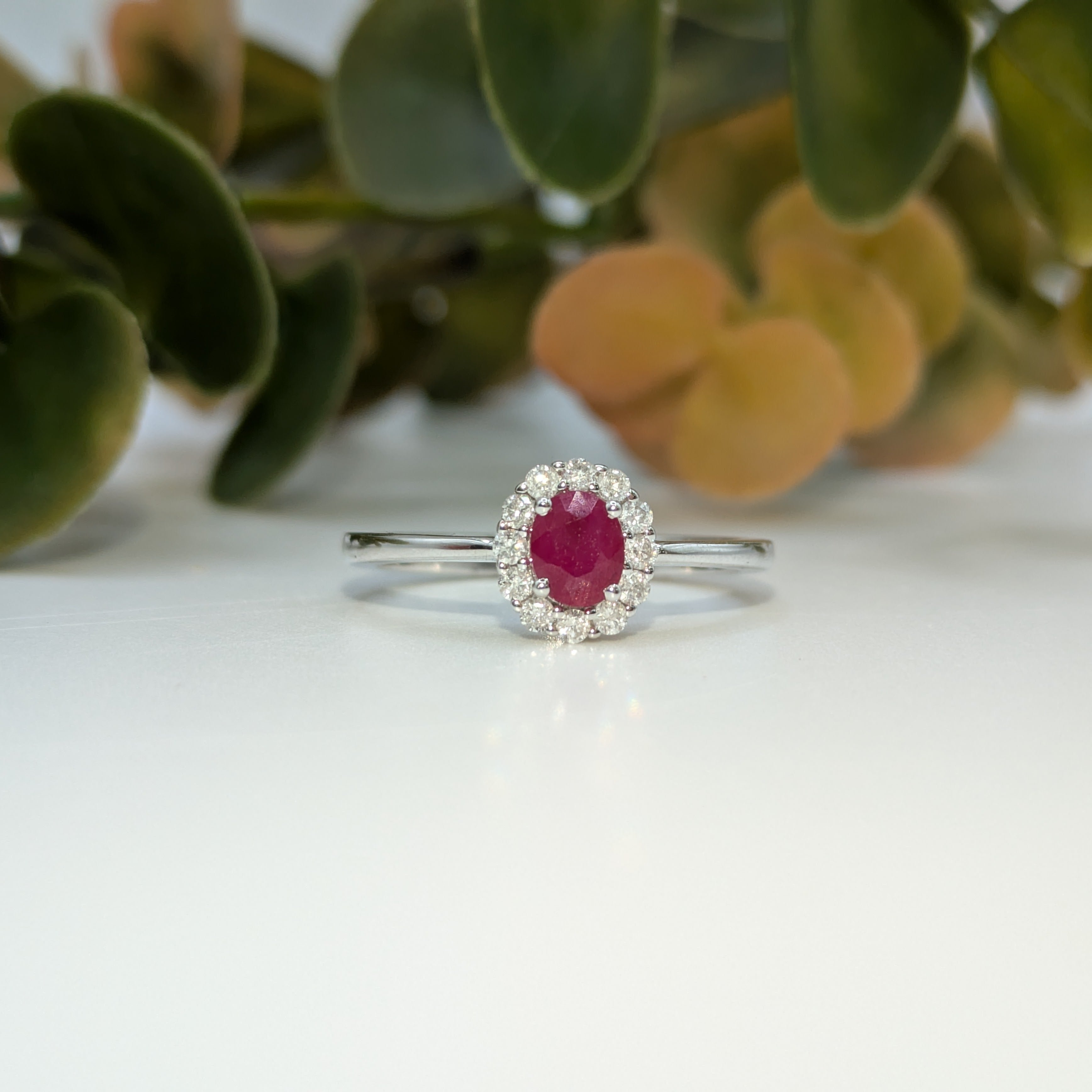 Oval cut ruby in diamond halo on 9k white gold