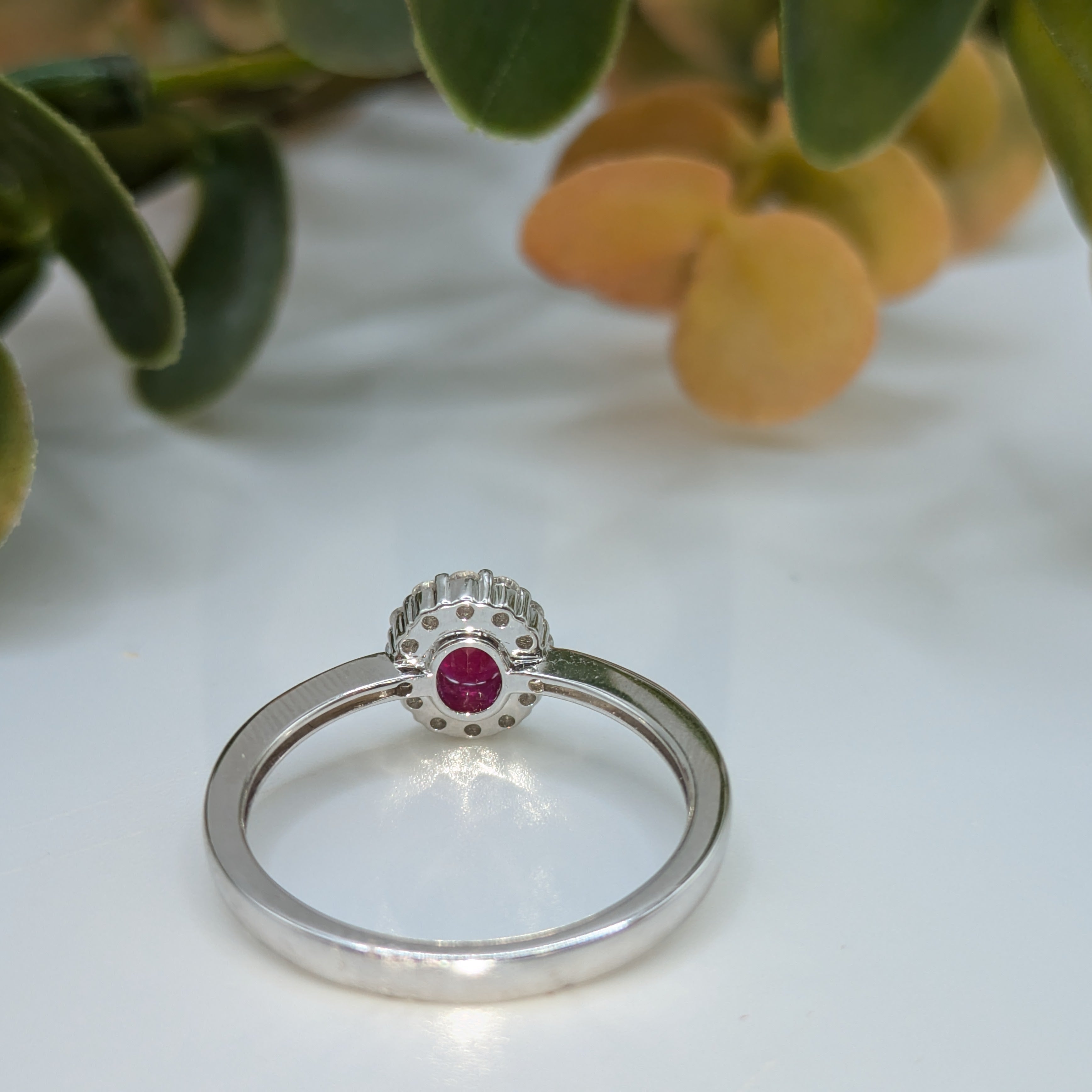 Oval cut ruby in diamond halo on 9k white gold